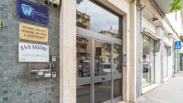 Une façade d’immeuble ornée de nombreuses enseignes commerciales, notamment celles d’un cabinet dentaire et d’un service de location de pianos.