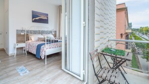 Una camera da letto con un letto, un comodino, una finestra e un balcone con vista sulla città.