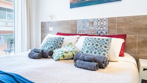 A neatly made bed with patterned pillows, a view of a historic building through a window, and a tiled wall. - Guest House 'Raudino Rooms - Maniace' with Balcony, Wi-Fi and Air Conditioning (Siracusa)