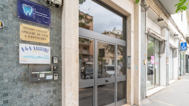 Facciata di un edificio con diversi cartelli pubblicitari, tra cui uno studio dentistico e un servizio di noleggio pianoforti.