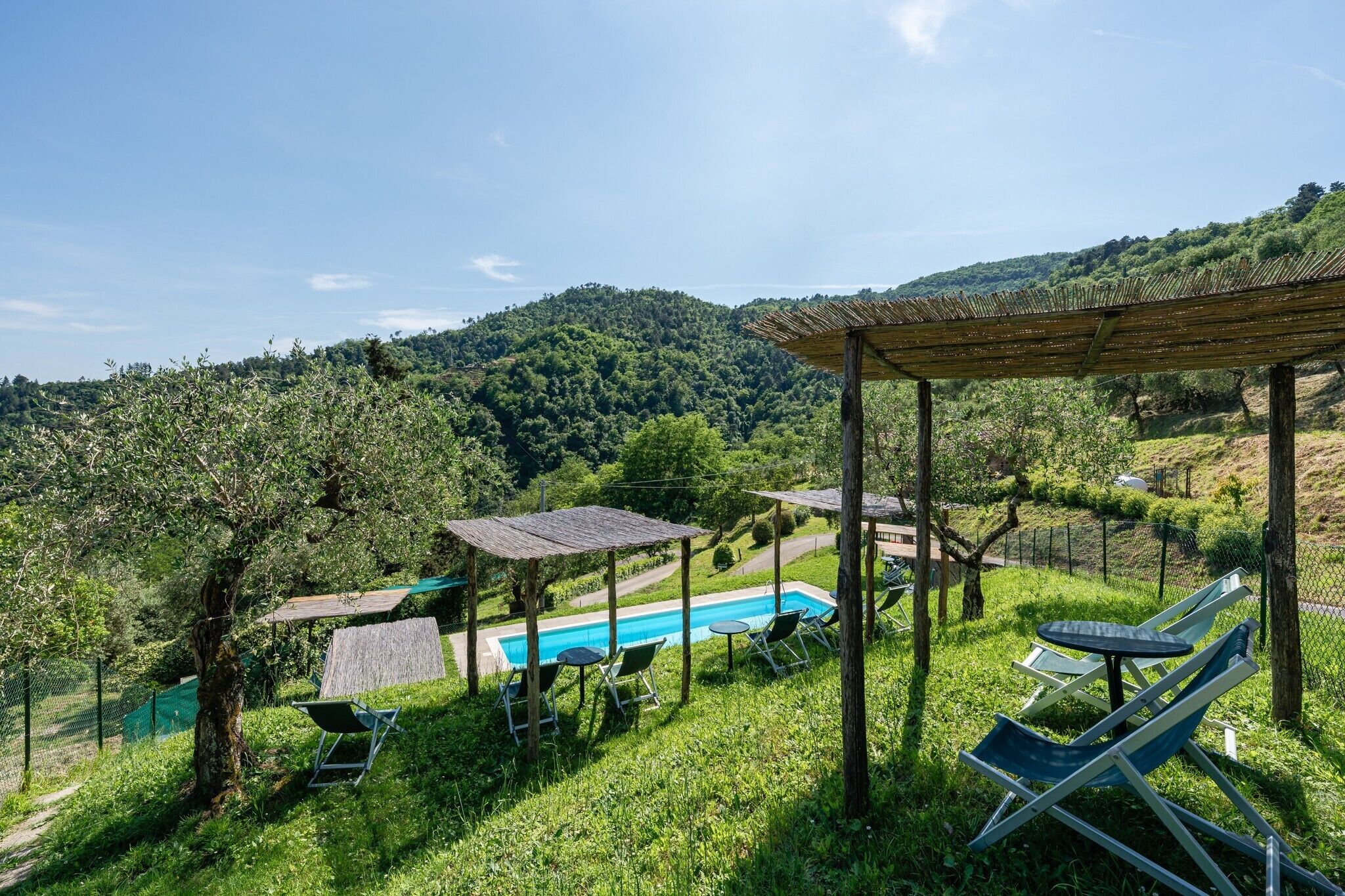 Un área de piscina con sillones de descanso y una pérgola.