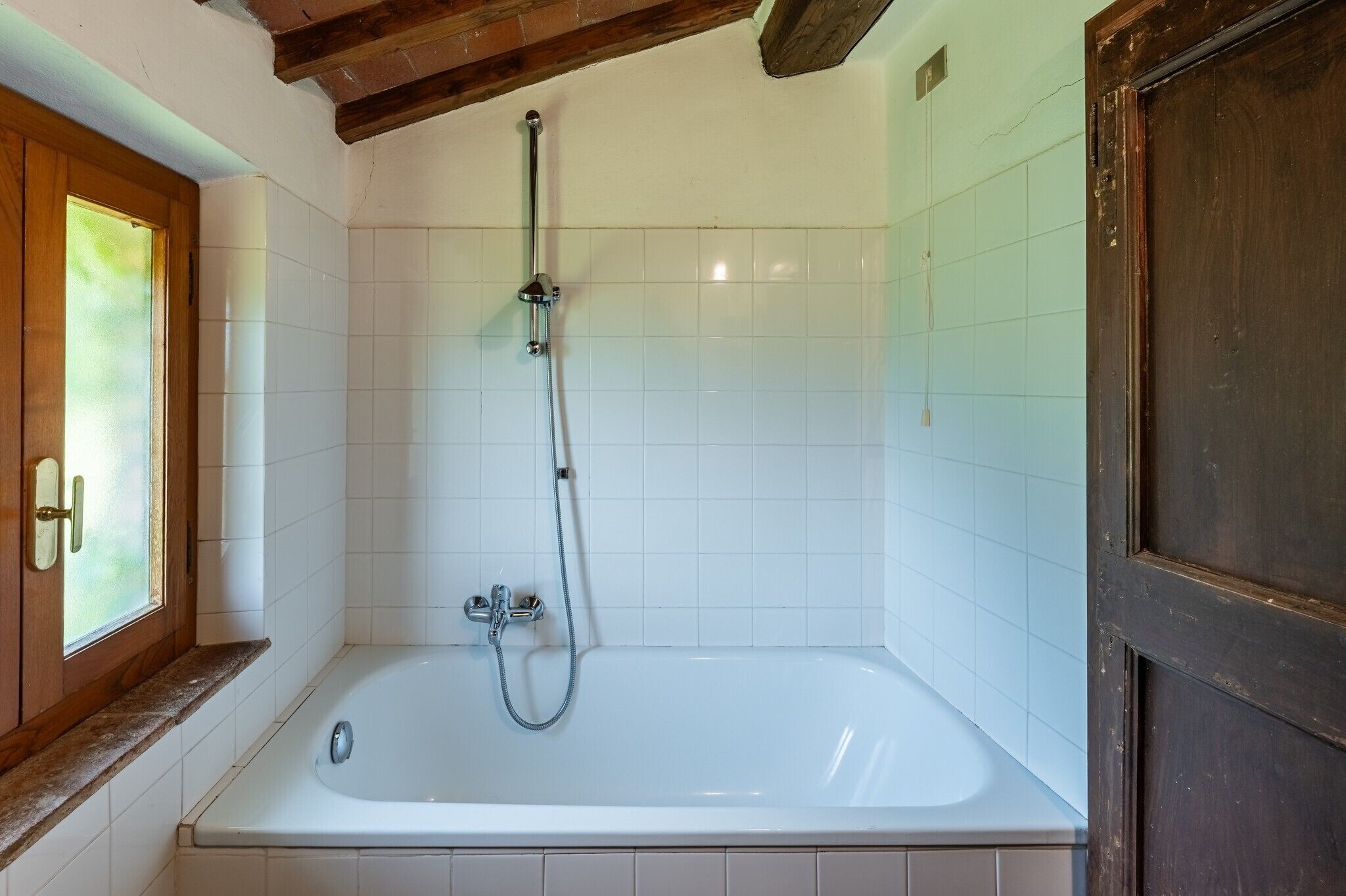 Une salle de bain avec une baignoire, une douche et une porte en bois.