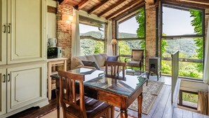 Un intérieur rustique comprenant une table à manger, des chaises, un canapé et une vue sur un paysage montagneux, visible à travers de grandes fenêtres.