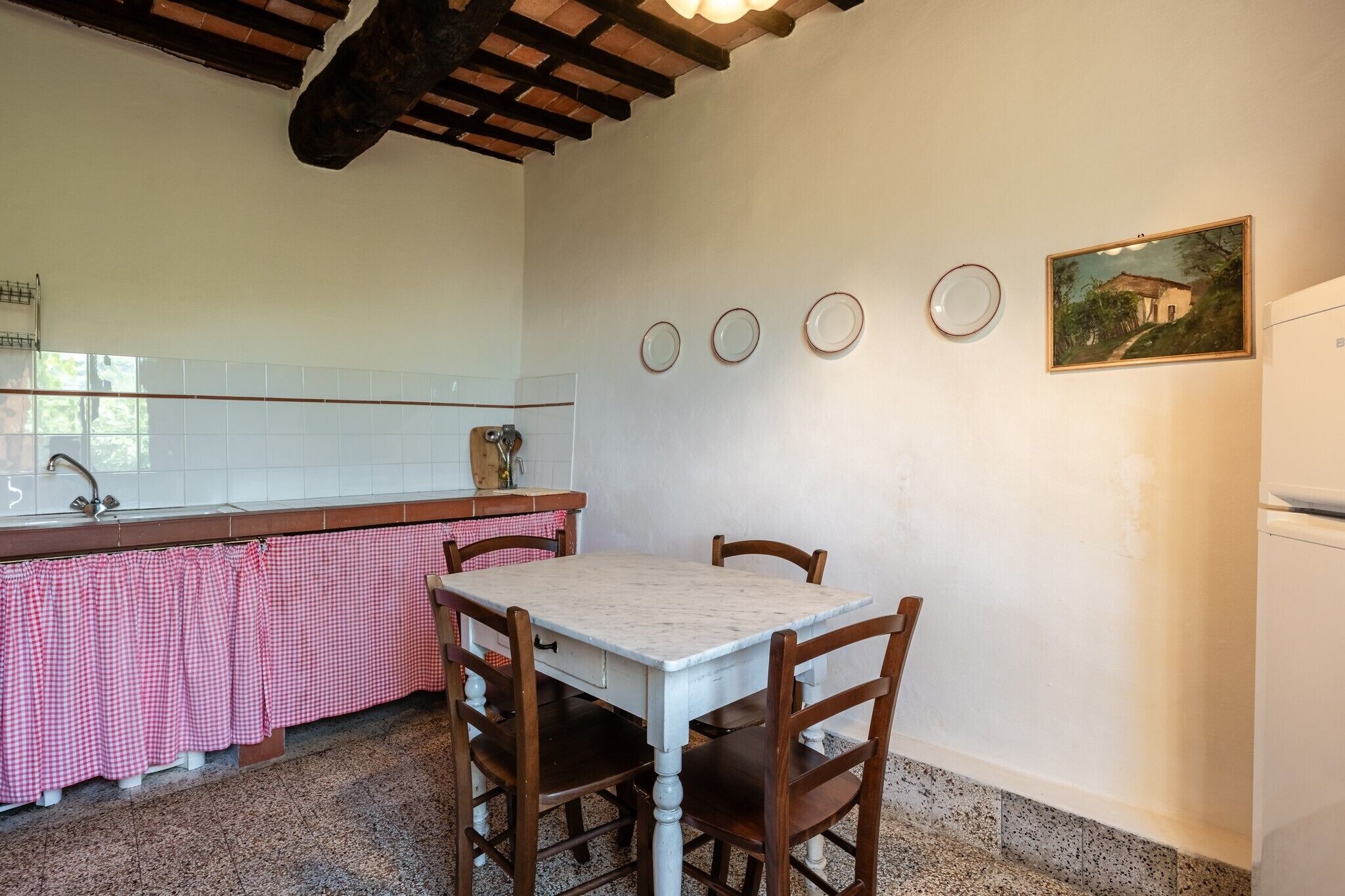 Une cuisine équipée d’une table, de chaises, d’un évier et d’un réfrigérateur.