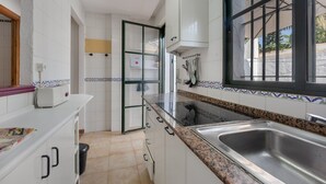 Une cuisine avec des meubles blancs, un plan de travail en granit, un évier en acier inoxydable et une fenêtre donnant sur l’extérieur.