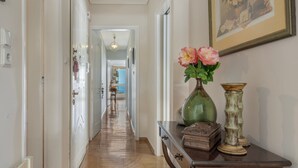 A hallway with a wooden floor, a vase with flowers, a decorative box, and a framed picture on the wall.