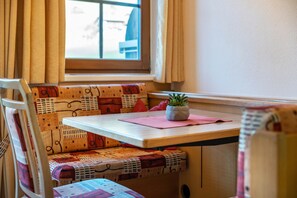 Een gezellig zithoekje met een tafel, een plant in pot en decoratieve kussens.