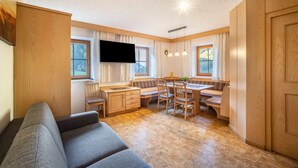 A compact living space with a sofa, dining table, chairs, and a TV.