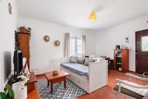 A compact room with a bed, a desk, a chair, a television, and a cabinet.