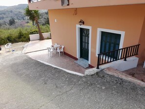Un bâtiment doté d’un balcon, d’une porte et d’une petite table avec des chaises.