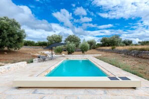 A rectangular swimming pool with a stone deck, surrounded by trees and a stone wall. - Apartment 'Sabrina Resort' with private pool, Wi-Fi and air conditioning (locorotondo)