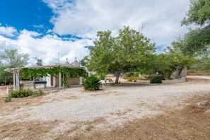 A building with a covered outdoor area, surrounded by trees and a gravel path. - Apartment 'Sabrina Resort' with private pool, Wi-Fi and air conditioning (locorotondo)