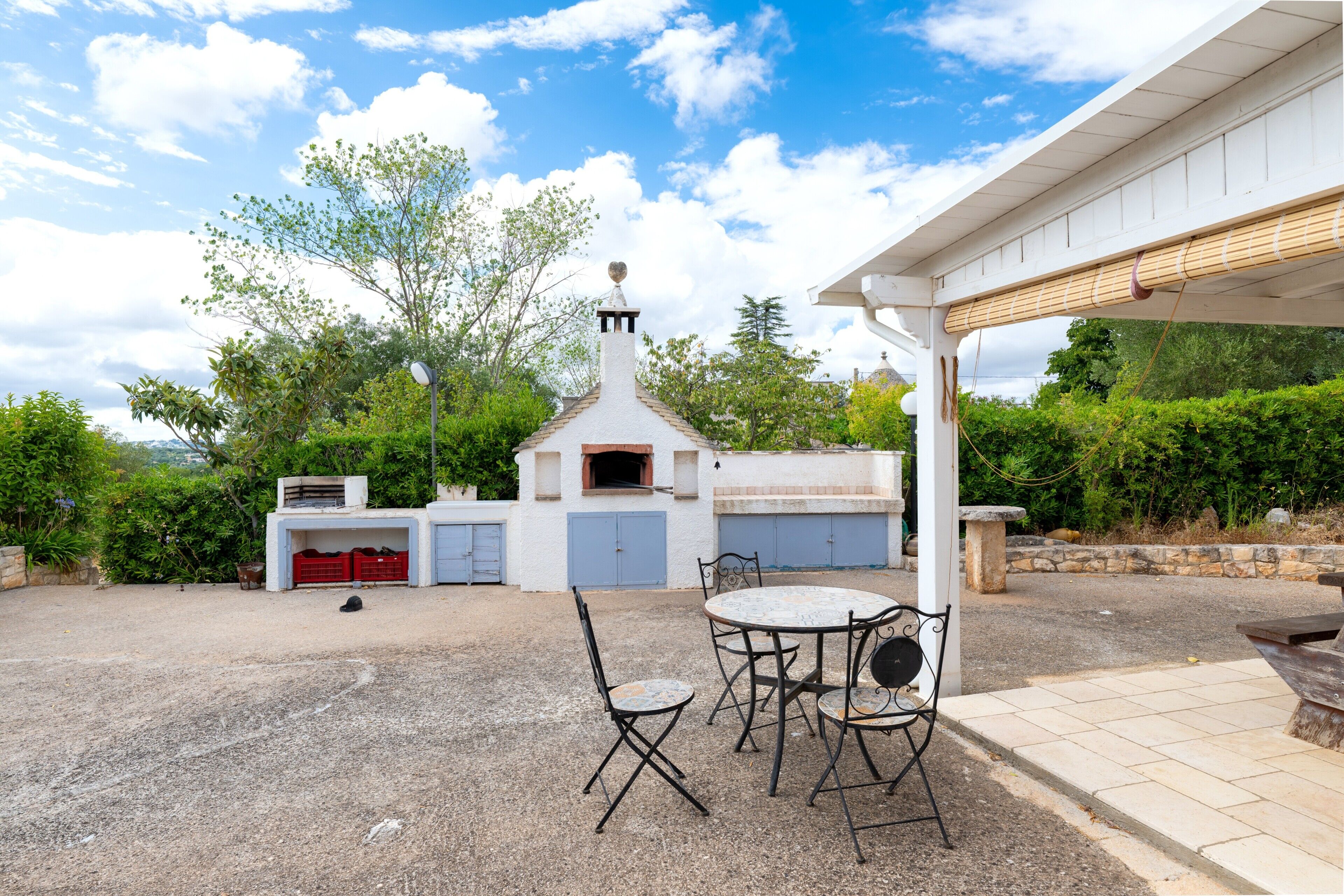 A patio with a table and chairs, a barbecue grill, and a chimney.
