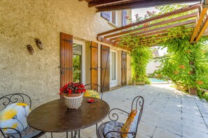 Une terrasse avec une table et des chaises, une pergola et une vue sur une piscine.