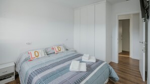 A bedroom with a bed, a nightstand, a wardrobe, and a door leading to another room. - Holiday Home 'La Isi' with Private Garden and Wi-Fi (Rades de Abajo)