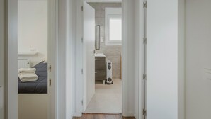 A hallway leading to a bedroom with a bed, a radiator, and a white heater.