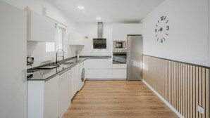 A modern kitchen with white cabinetry, a stainless steel oven, and a microwave.