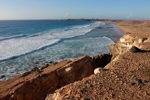 Un paisaje costero con terreno rocoso y una playa.