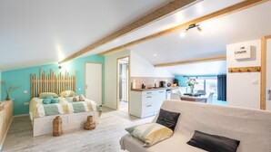 Un salon moderne comprenant un canapé, un lit, un coin cuisine et une vue sur l’extérieur.