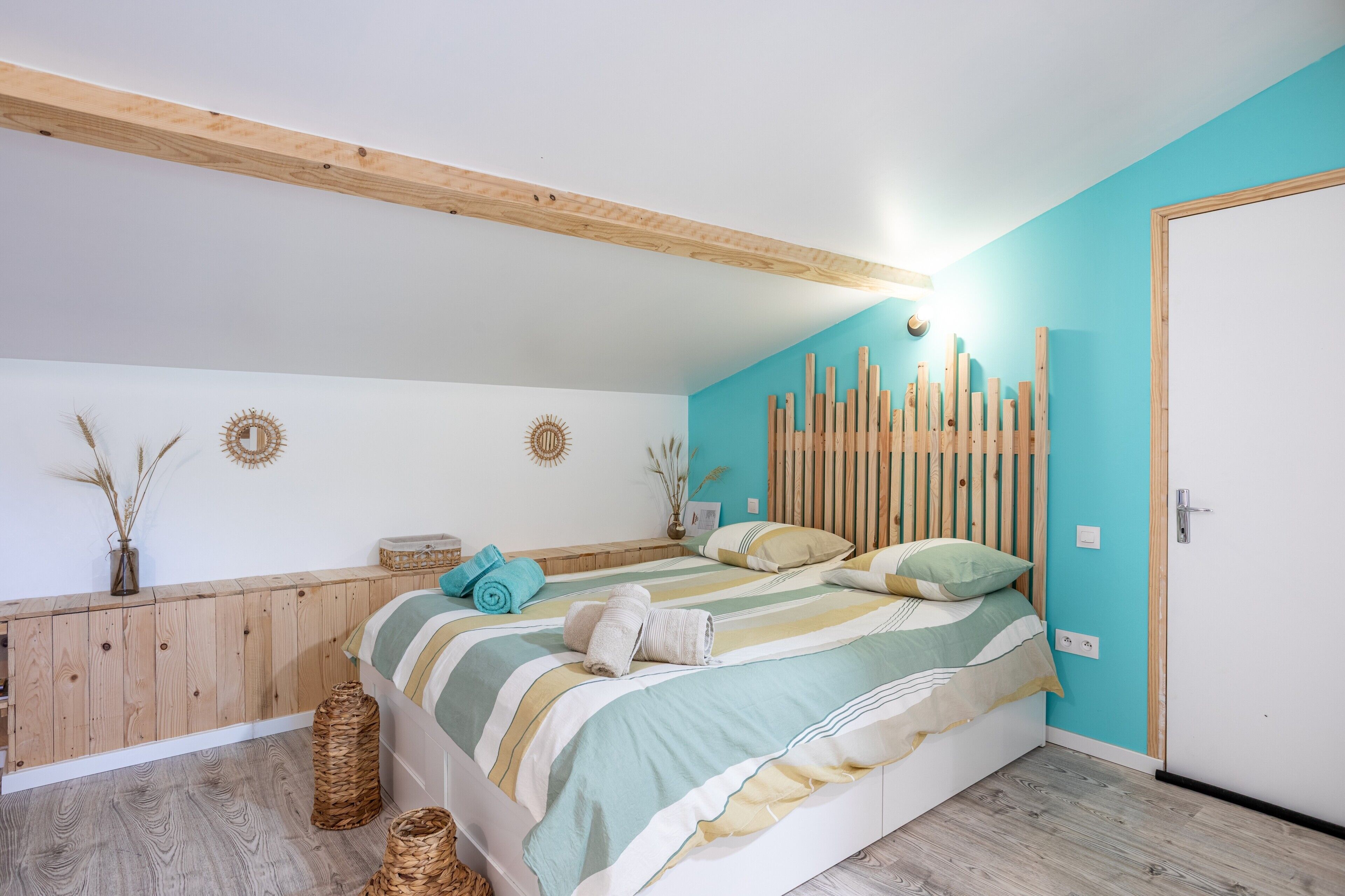 Un dormitorio con cama, cabecero de madera, decoración en la pared y una puerta.