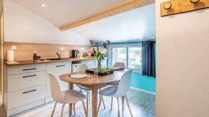 Une cuisine moderne avec des meubles blancs, un plan de travail en bois et un coin repas comprenant une table et des chaises en bois.