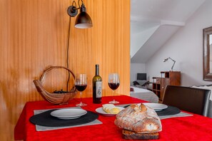 Uma mesa de jantar com toalha vermelha, dois copos de vinho, uma garrafa de vinho, uma cesta de mirtilos, um pão e um prato de manteiga.