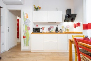 Een moderne keuken met witte kasten, een houten aanrecht en een rode stoel.