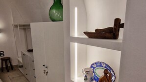 A modern kitchen with white cabinetry, a green bottle on the upper shelf, and various kitchen utensils and dishes on the lower shelves. - B&B La Casa Di Bianca (Manfredonia)