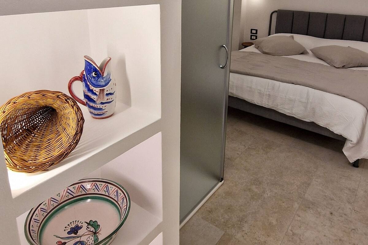 Ein modernes Schlafzimmer mit einem Bett, einer Glastür und einem Regal mit Dekoration.