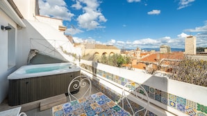 Une terrasse sur le toit avec un jacuzzi, une vue sur la ville et un mur recouvert de carreaux.