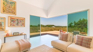 A modern living room with a large window, a sofa, a coffee table, and artwork on the wall.