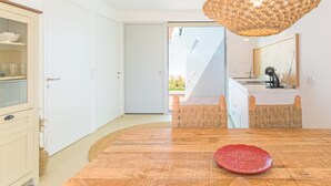 Et moderne køkken med et træbord, en hængende lampe og udsigt til det fri.