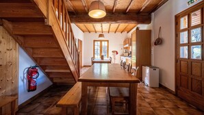 A wooden interior with a dining table, benches, a staircase, and a fire extinguisher. - Chalet 'Savoiage' with Mountain View, Private Terrace and Wi-Fi (Saint-Colomban-des-Villards)