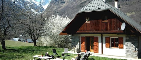 A rustic mountain cabin with a stone exterior, wooden shutters, and a sloped roof.