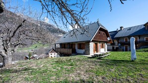 A rustic chalet with a stone facade, wooden balcony, and a view of a valley. - Chalet 'Savoiage' with Mountain View, Private Terrace and Wi-Fi (Saint-Colomban-des-Villards)