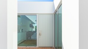 Een modern uiterlijk met een schuifdeur, een witte deur en een betegeld terras.
