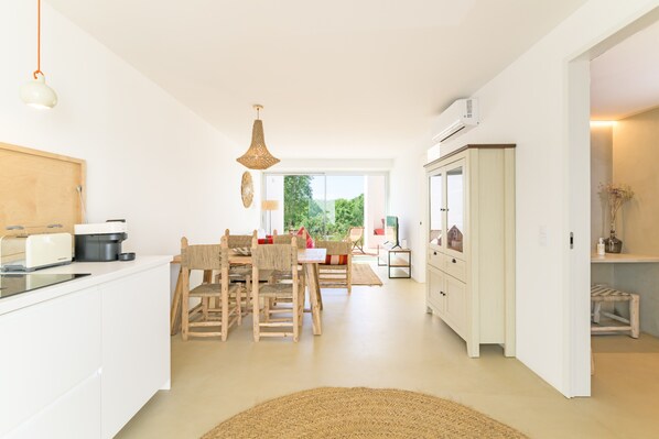 A spacious kitchen with a dining area, white cabinetry, and a large window.