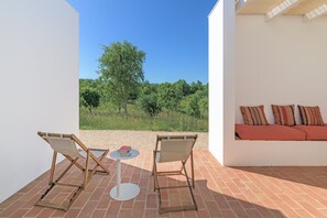 A patio with two chairs, a small table, and a sofa with cushions.