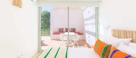 Una habitación de hotel con cama, ventana y vista a un área de estar exterior.