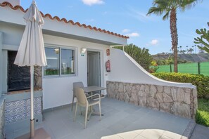 A patio with a table and chairs, a fire extinguisher, and a stone wall.