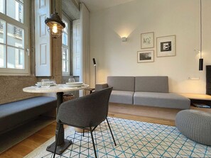 Cozy living area with a round dining table for two, comfortable sofa, and armchair, plus a bench for extra seating.