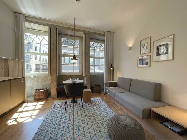 Cozy living space with a seating area, kitchenette, and large windows offering views of the surrounding buildings.