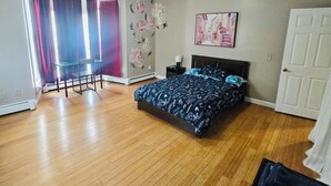 Un dormitorio con cama, una silla, chimenea y puerta.
