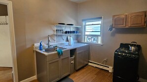 Una cocina compacta con estufa, lavamanos y ventana.