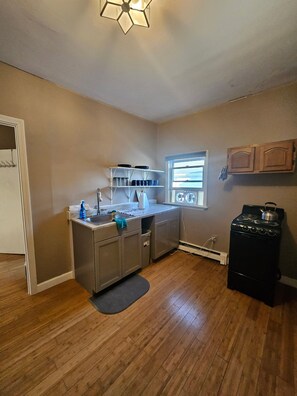 A compact kitchen with a stove, sink, and window.