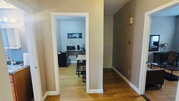 Amplia sala de estar con pisos de madera, una cocina al fondo y un comedor con mesa y sillas.