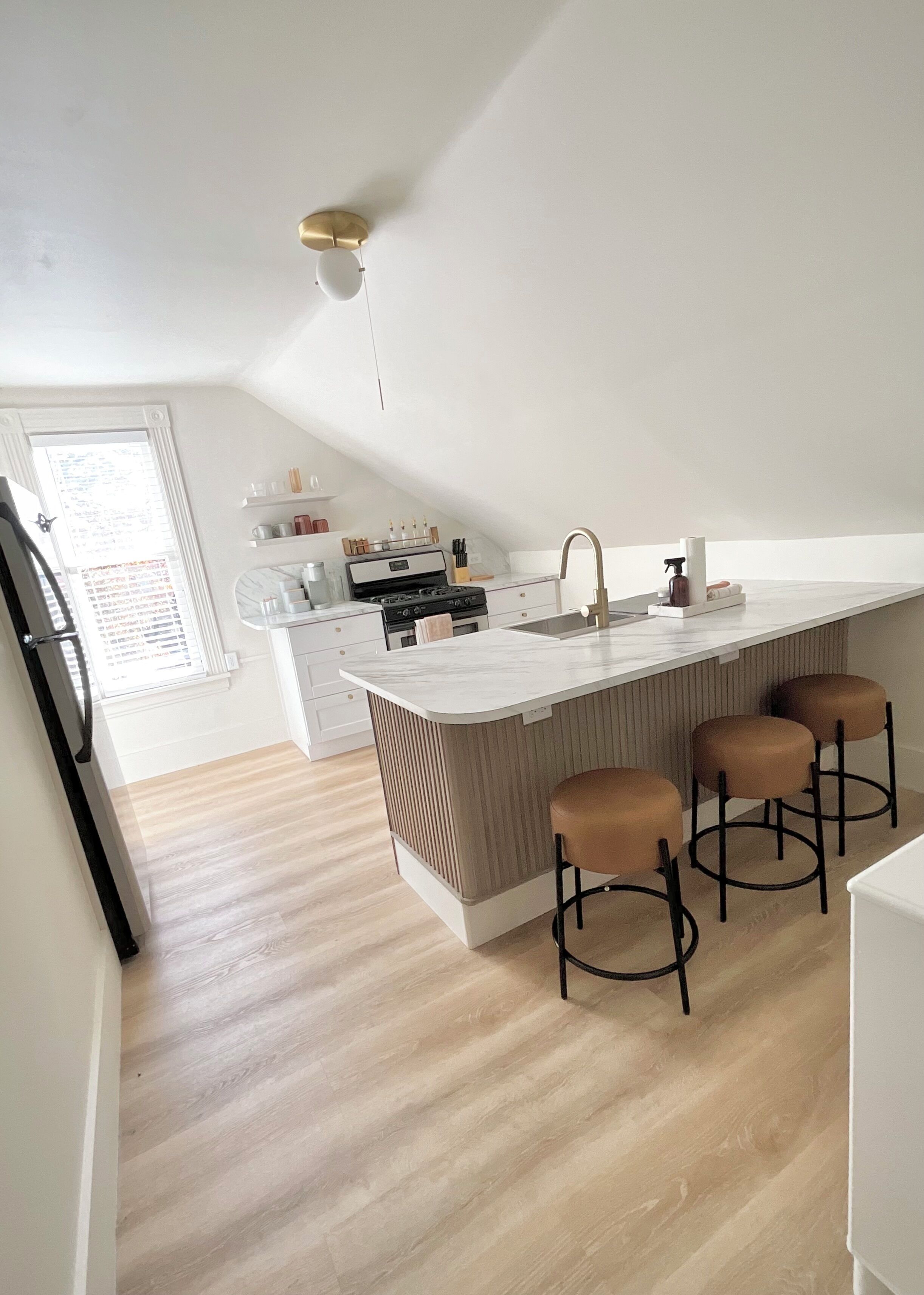 Een moderne keuken met een centraal eiland, barkrukken en een geïntegreerde kookplaat.