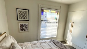 A bedroom with a bed, a window with blinds, and a ceiling light fixture. - Next Level Convenience in Grand Rapids premier neighborhood (Grand Rapids)