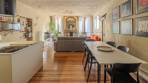 Et moderne køkken med en central ø, et spiseområde med bord og stole, en sofa og en pejs.