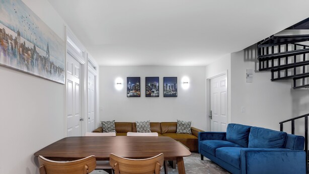 Un comedor con una mesa y sillas de madera, un sofá azul y una escalera.
